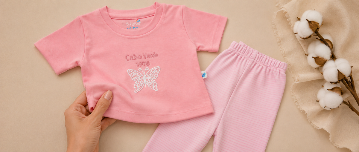 A mother feeling the fabric of babyron butterfly pyjama set for baby girls and a cotton nud placed on the side showing how soft and premium the baby clothes are